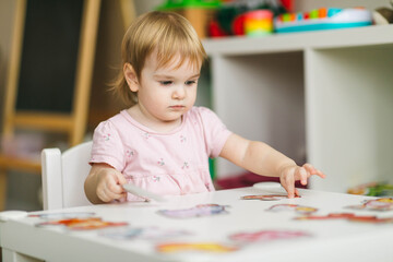 A one-year-old girl sits at the table and draws. How to develop a child