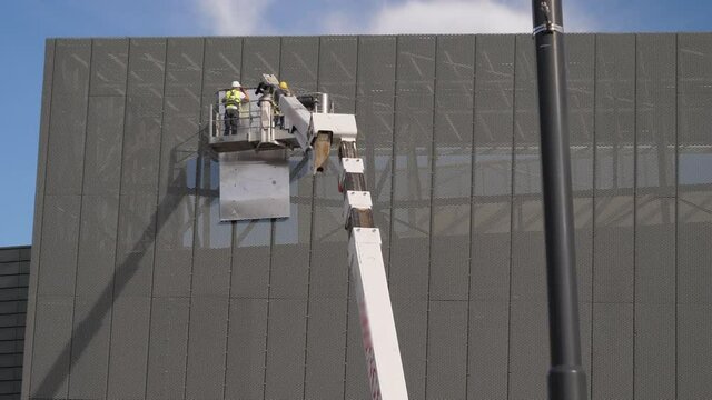 Workers are installing a safety net with the help of the telescopic boom from the lifts platform