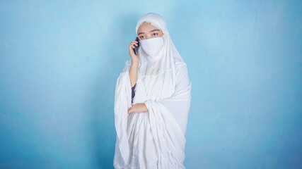 Ied Fitr / Ied Mubarak Concept - Asian Hijab Woman talking on cellphone. Coronavirus pandemic time.