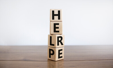 Help is here symbol. Turned cubes and changed the word help to here. Beautiful wooden table, white background, copy space. Business, motivational and help is here concept.