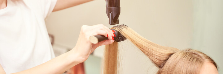 Repair long hair procedure. Haircut at salon. Woman hairstyle. Master hand with brush and fan. Adult female person. Closeup view. Studio equipment. Lady preparation. Blonde dry. Copyspace