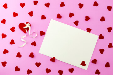 Fototapeta na wymiar Confetti hearts on pink background with postcard and copy space. Red decorative heart. There was plenty of room for text in the apartment. The concept of Valentine's day
