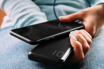 Fototapeta premium The woman plugged the charger with the phone in office or at home. Power Bank.