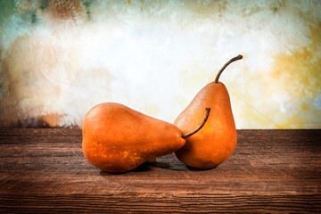 Two large yellow bosc pears on a barn wood table