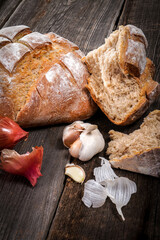 Country bread, garlic cloves and french dry shallots on a barn wood board