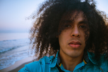 Retrato de chico de cabello largo rizado en la playa