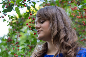 Naklejka premium Portait of cute teen girl with makeup posing in cherry garden