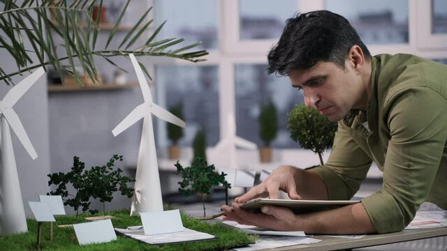 Man working with wind turbines and solar panels environmental project using tablet