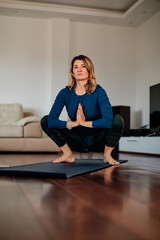 A middle-aged woman in goddess yoga pose practicing yoga at home.