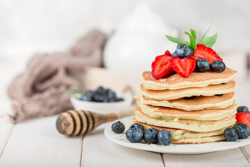 Classic american pancakes with fresh berry on white wood background. Summer homemade breakfast.