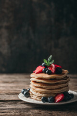 American pancakes with fresh berry on wood background. Summer homemade breakfast.