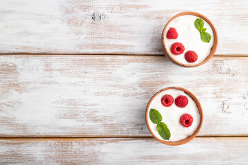 Yogurt with raspberry in clay cups on white wooden background. top view, copy space.