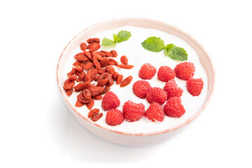 Yogurt with raspberry and goji berries in ceramic bowl isolated on white background. Side view.