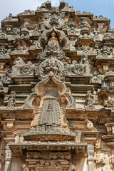 Fototapeta na wymiar Lakkundi, Karnataka, India - November 6, 2013: Kasivisvesvara Temple. Extensive brown-gray stone sculptures on side of vimanam above main entrance. 