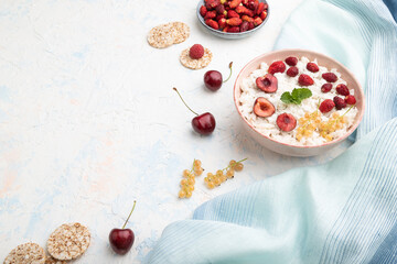 Rice flakes porridge with milk and strawberry in ceramic bowl on white concrete background. Side view, copy space.