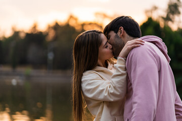 happy couple kissing at sunset in urban park. concept day of love and friendship