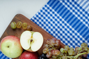 Red green apples and grape bunches on a wooden board