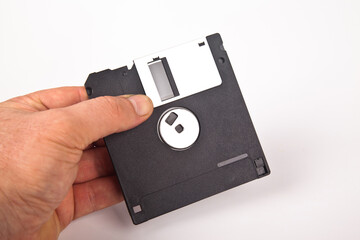 Old computer and data storage technology, hand held black magnetic floppy disk 3½ inches, isolated...