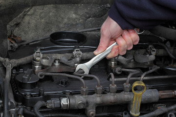 Worker fixing modern common rail diesel engine, closeup of hand with spanner tool, rail, pipeline and injectors