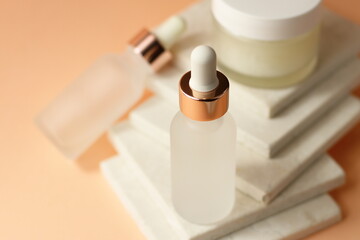Transparent cosmetic bottles with pipette on natural stone marble background,  organic spa on peach color texture, copy space 