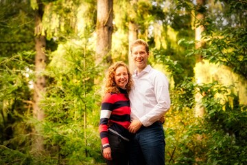 A young man and woman in love are standing in the forest. The couple stands with their arms around each other