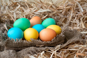 Naklejka na ściany i meble Easter eggs of different colors in a nest made of burlap. Close-up. Happy Easter