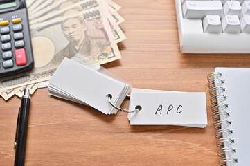 On the desk were Japanese yen bills, a keyboard, a notebook, and a word book with the word APC written on it. It was an abbreviation for the financial term Average Propensity to Consume.
