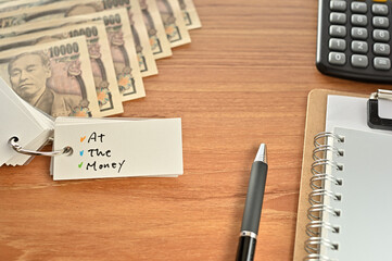 On the desk were Japanese yen bills, a calculator, a notebook, and a word book with the word ATM written on it. It was an abbreviation for the financial term at the money.