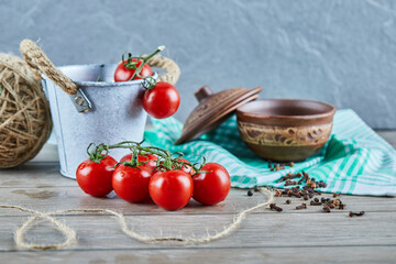 Bucket of tomatoes and cloves on wooden table with empty bowl