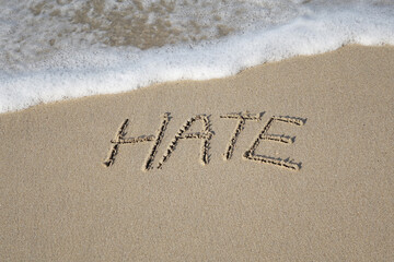 Beach sand messages : Hate written in the sand on beach with wave. Concepts photography. Selective focus 