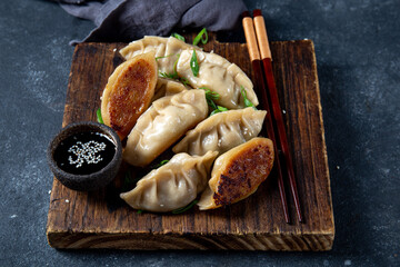 Asian dumplings Gyoza potstickers on old wooden board. Top view, copy space