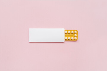Hormonal oral contraceptives pills in a blister for a month of reception lie on pastel pink background. Flat lay, top view, copy space.