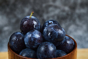 Garden plums in a bowl on dark background