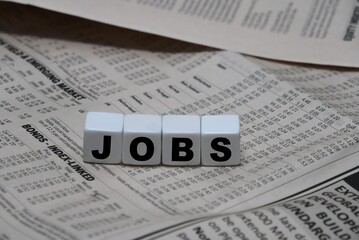 dice with letters JOBS on a newspaper - job search & application