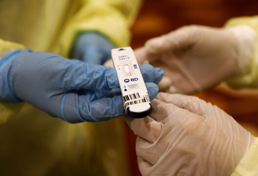 Healthcare workers hold a coronavirus disease (COVID-19) antigen rapid test cartridge at a testing station for attendees of a conference held by the Institute of Policy Studies at Marina Bay Sands Convention Centre in Singapore