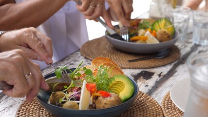 Two people eating with cutlery their vegan Buddha bowl. Healthy plant based diet