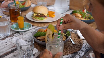 Vegan group lunch. People drinking ice tea from glass jars and eating healthy plant based meals