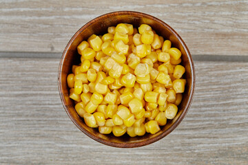 A bowl of boiled sweet corn on a wooden table
