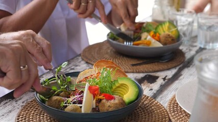 Two people eating with cutlery their vegan Buddha bowl. Healthy plant based diet