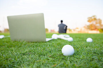 Golf balls on a green lawn in a beautiful golf course with laptop for search information and player...