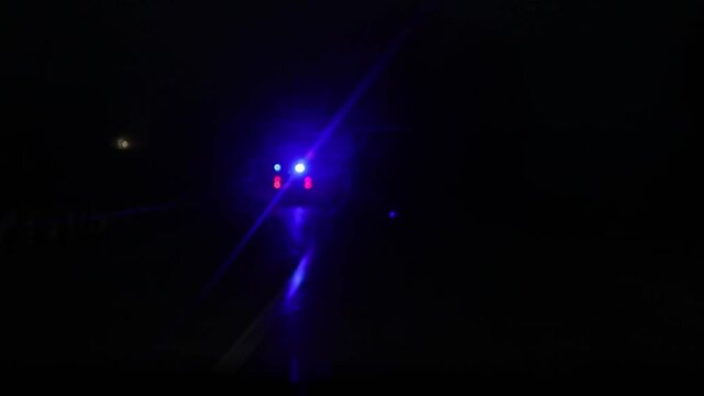 Parallel Moving Of An Ambulance Vehicle With Working Strobe Light And Signal Driving To Emergency Call On A Country Road At Night. Shot From Other Car