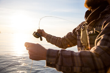 A close up of a fly fisherman wearing a plaid shirt, holding a rod and reel while wading in the water in Vancouver, British Columbia - Powered by Adobe
