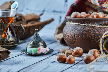 A bowl of hazelnuts on blue wooden table with sweets