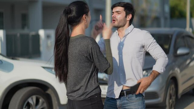 Two angry motorists arguing after a car accident on the road calling insurance company on mobile phone to responsibility for car accident traffic collision. furious driver man shouting to stress woman