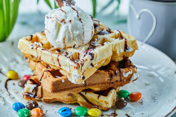 Waffles with ice-cream, chocolate, M$M's on the white plate with tea