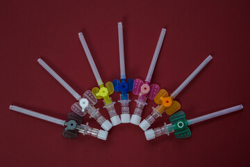 intravenous catheters on a red background, shot close-up. multicolored catheters have different diameters - from the smallest to the largest