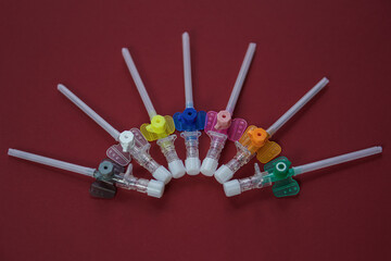 intravenous catheters on a red background, shot close-up. multicolored catheters have different diameters - from the smallest to the largest