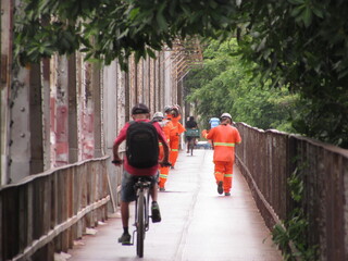 person riding a bike and workers walking