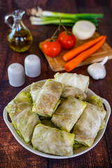 Raw cabbage rolls (stuffed cabbage) with meat and rice on a white plate. 