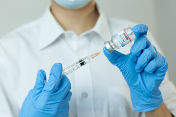 COVID-19 vaccine concept of fight against coronavirus. Doctor or nurse in medical gloves with a coronavirus vaccine bottle and syringe.